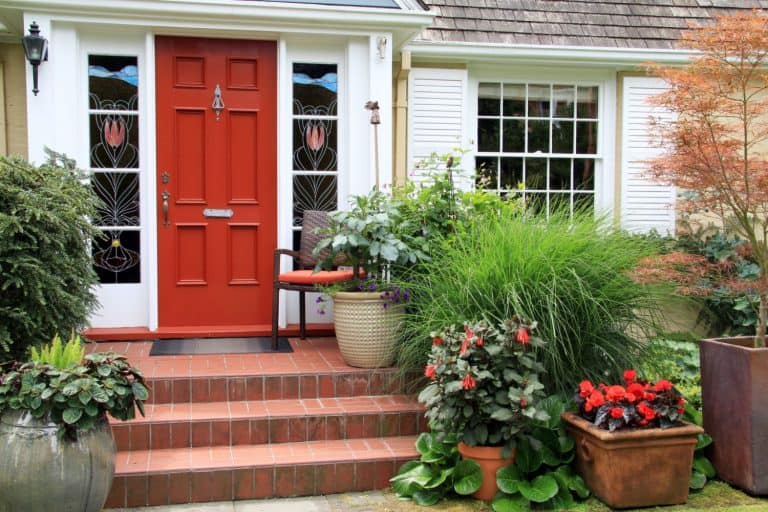 red front door with brick stoop and landscaping