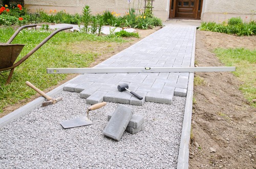 Bricklayer Places Concrete Paving Stone Blocks For Building Up A Walk way